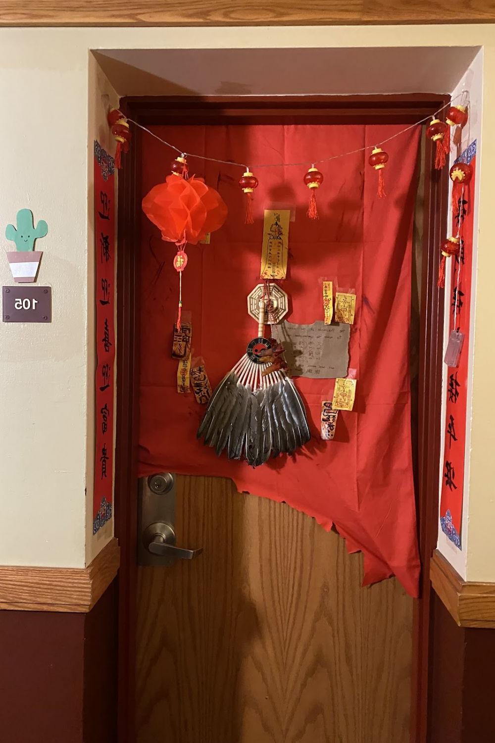 A dorm door decorated in Chinese lanterns and talismans, and a dead hand.